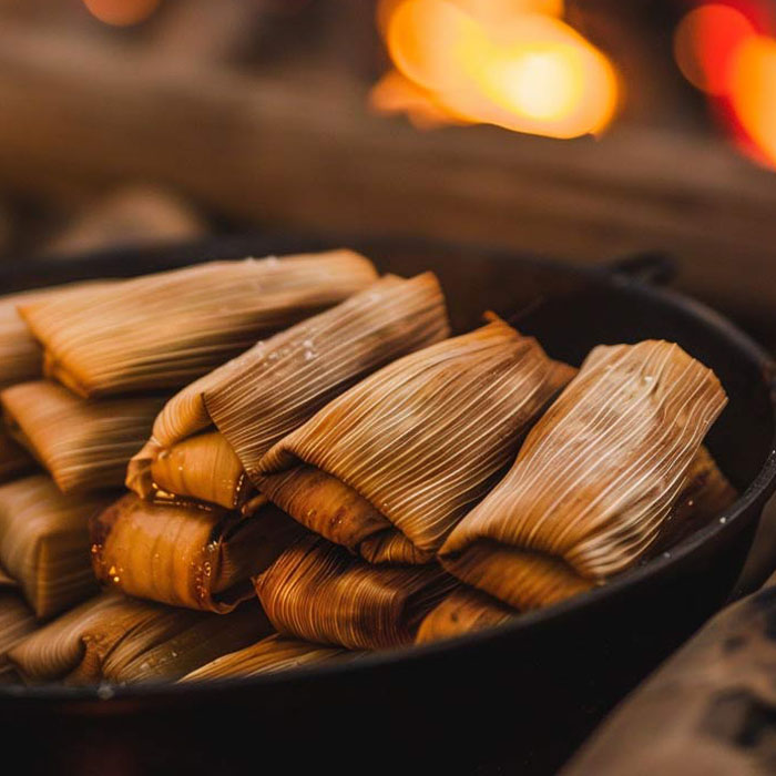 Ein Teller mit traditionellen mexikanischen Tamales, serviert mit einer würzigen Sauce.